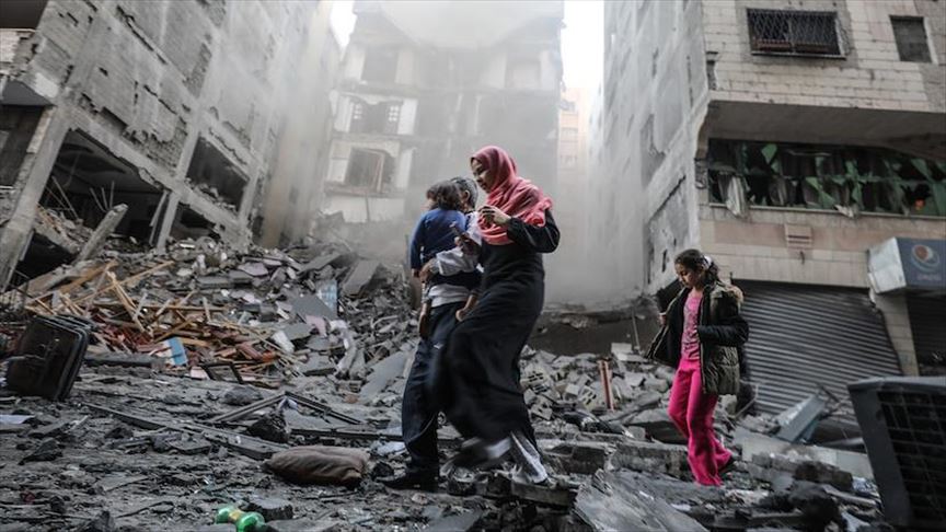Warga Gaza melintas di antara reruntuhan bangunan yang terkena serangan Israel. ( Mustafa Hassona - Anadolu Agency )