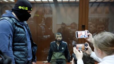 Shamsidin Fariduni, tersangka penembakan di tempat konser Balai Kota Crocus, duduk di balik dinding kaca kandang terdakwa sebelum sidang pengadilan di pengadilan distrik Basmanny di Moskow, Rusia 25 Maret 2024. (REUTERS/Shamil Zhumatov)