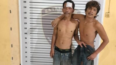 Komplotan maling besi rel kereta api Eldy Pandre (46) dan Abdul Hasim Nasution (32) masih sempat berpose di kantor polisi usai digebuki warga.