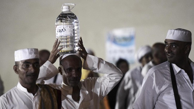 Jemaah haji memanggul sebotol air zamzam di Mekkah, 2014. Benarkah air ini punya khasiat? (AFP/MOHAMMED AL-SHAIKH