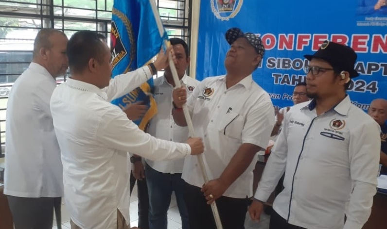 Ketua PWI Sumut H Farianda Putra Sinik SE (kiri) menyerahkan bendera pataka PWI kepada ketua terpilih.(Ist)