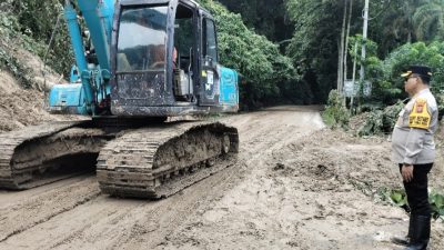 Kombes Pol Gidion Arif Setyawan memantau alat berat membersihkan jalan yang masih berlumpur.(ist)