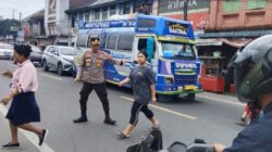 Personel polisi bantu pejalan kaki menyeberangi jalan.(ist)