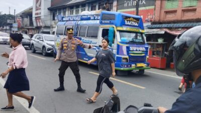 Personel polisi bantu pejalan kaki menyeberangi jalan.(ist)