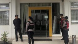 Petugas kepolisian berjaga di depan pintu masuk kantor Dinas PUPR Sumut